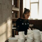 Focused artisan in ceramics studio among handcrafted bowls and pottery.
